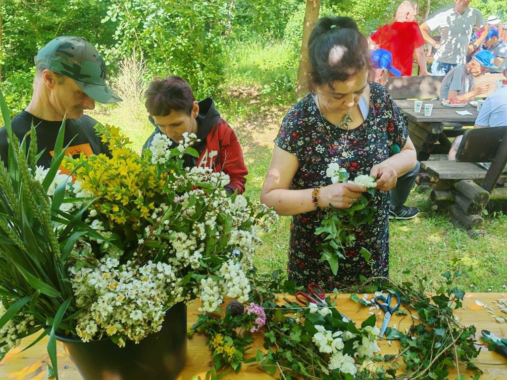 Uczestnicy pikniku wspólnie przygotowują wianki z polnych kwiatów.