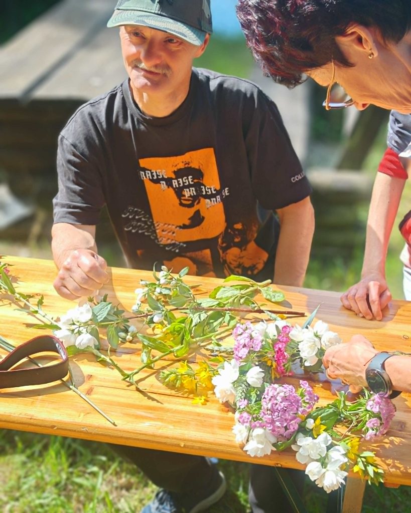 Uczestnik pikniku sobótkowego układa kolorowe kwiaty na stole.