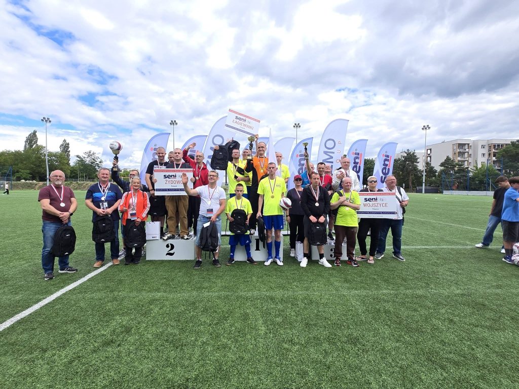 Zawodnicy DPS Żydowo podczas ceremonii zakończenia turnieju Seni Cup stoją na podium z medalami, pucharami i dyplomami.