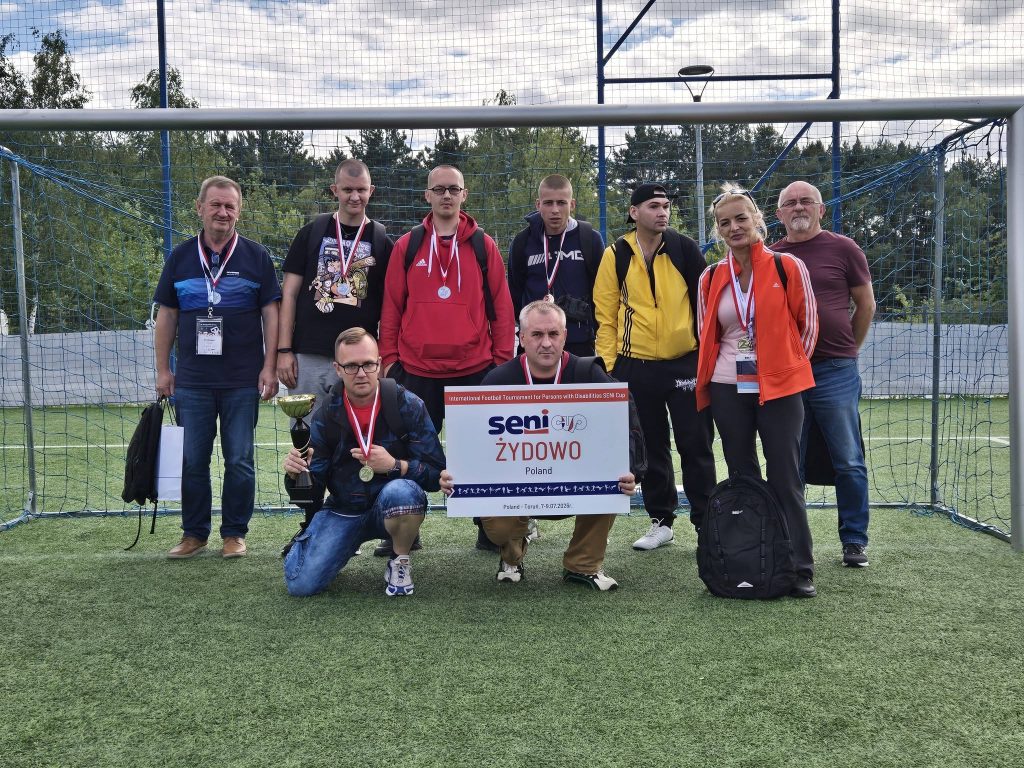 Drużyna DPS Żydowo po zakończeniu turnieju Seni Cup pozuje do wspólnego zdjęcia z pucharem, medalami i tablicą z nazwą drużyny.