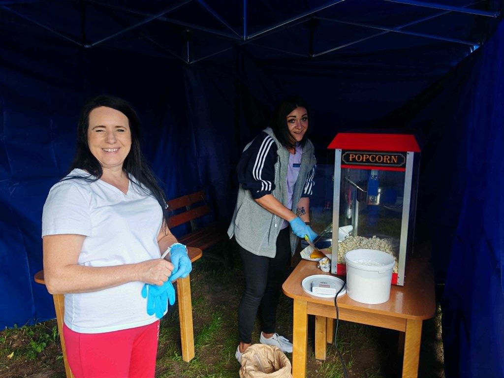 Dwie pracownice DPS Żydowo przygotowują popcorn w namiocie podczas organizacji kina plenerowego dla mieszkańców.